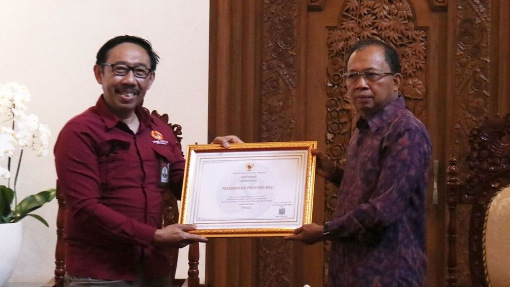 Ketua KASN Agus Pramusinto (kiri) menyerahkan sertifikat penghargaan kepada Gubernur Bali Wayan Koster (kanan) atas hasil pengukuran Indeks Maturitas Penerapan Nilai Dasar, Kode Etik, dan Kode Perilaku (IM NKK) ASN di Gedung Jaya Sabha, Kota Denpasar, Rabu (6/7/2022).