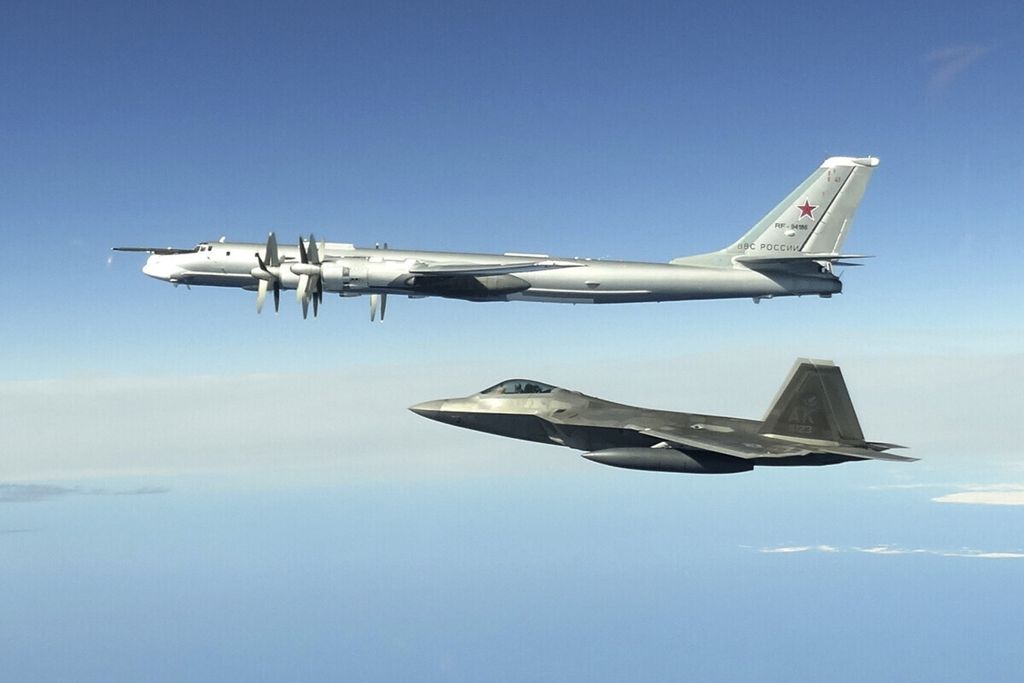 Dalam foto yang direkam pada 16 Juni 2020 ini, jet F-22 Raptor Amerika Serikat (bawah) mengiringi pesawat pengebom Tu-95 Rusia di wilayah udara Alaska, AS. Pada 12 Februari 2022, enam jet F-22 AS tiba di Uni Emirat Arab. 