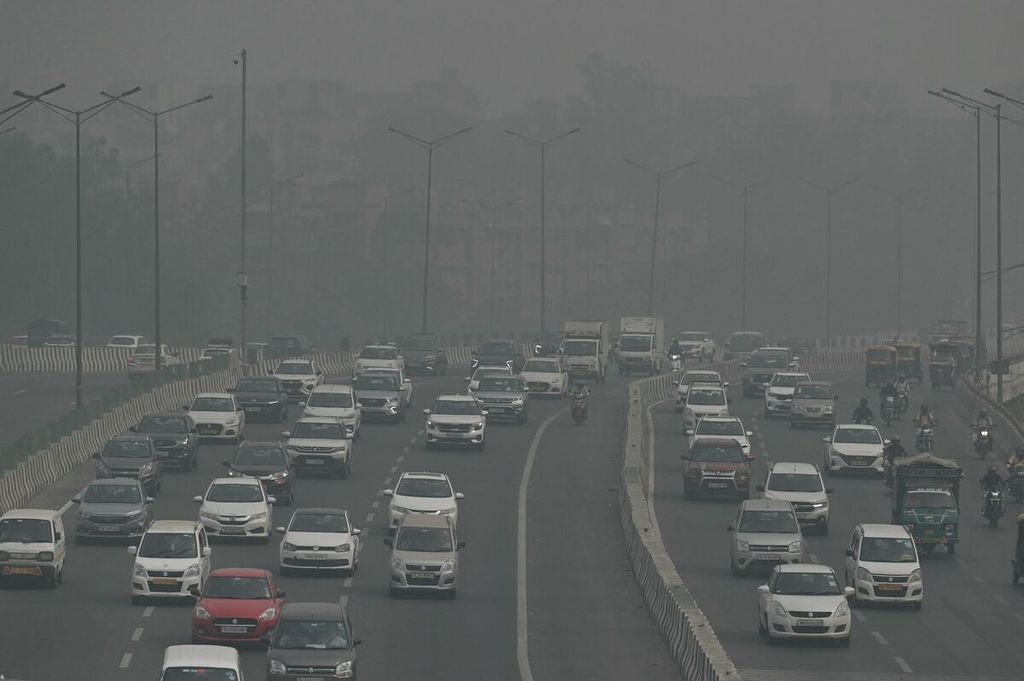 Para pengguna kendaraan di New Delhi, India, pada 9 November 2023, menembus asap pekat yang menyelimuti ibu kota negara itu. 