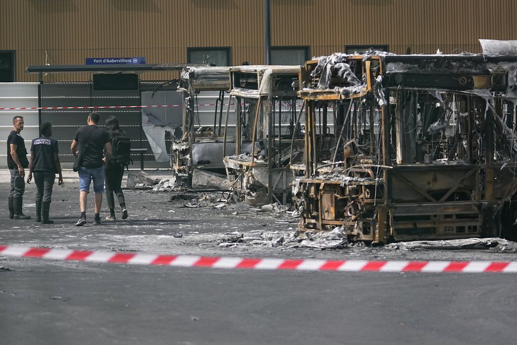 Polisi memeriksa sejumlah bus yang dibakar massa saat terjadi aksi kerusuhan di depot bus Aubervilliers, pinggiran kota Paris, Perancis, Jumat (30/6/2023). Pengunjuk rasa menuntut keadilan atas terbunuhnya remaja Nahel oleh polisi.