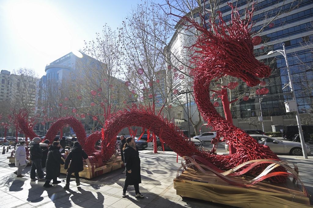 Warga berada di sekitar patung berbentuk naga. Struktur patung itu terbuat dari ranting-ranting pohon yang disusun sedemikian rupa seperri tampak di Beijing, China, Rabu (7/2/2024).