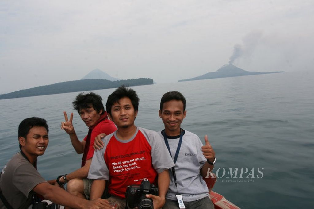 Wartawan<i> Kompas</i>, Yulvianus Harjono (kanan); fotografer <i>Kompas</i>, Heru Sri Kumoro (kedua dari kanan); dan fotografer senior <i>Kompas</i>, Eddy Hasby (ketiga dari kanan); dengan latar belakang Gunung Anak Krakatau yang mengeluarkan asap, Sabtu (24/7/2010).