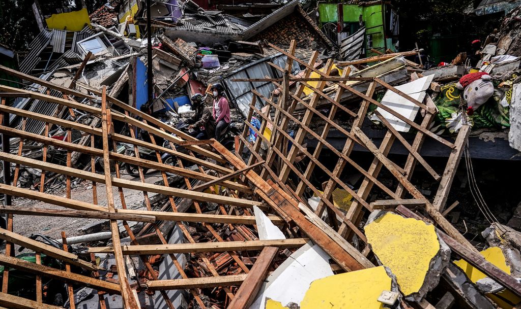 Warga melintasi reruntuhan di Desa Gasol, Cugenang, Kabupaten Cianjur, Jawa Barat, Selasa (22/11/2022). 