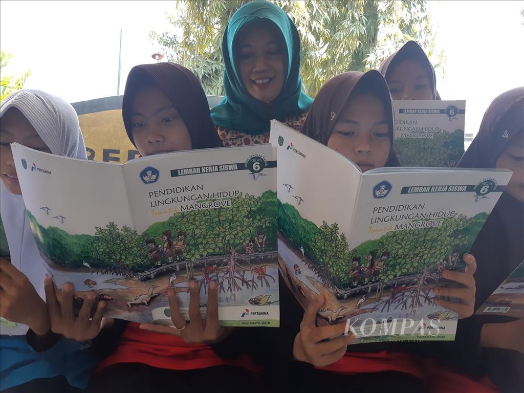 Kepala SD Negeri Paoman IV Lutfiya bersama siswa membaca buku terkait dengan mangrove di sekolah di Kabupaten Indramayu, Jawa Barat, Sabtu (25/5/2019). SD Negeri Paoman IV termasuk dalam 26 SD di Indramayu yang menerapkan kurikulum pendidikan lingkungan hidup tematik mangrove. Tahun ini, ditargetkan sebanyak 42 SD menerapkan hal serupa.
