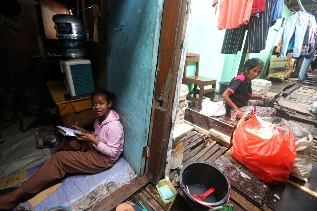 Nuraini, siswi SD kelas 6 sedang mengerjakan tugas sekolah di rumahnya yang berada di kawasan hunian semipermanen padat penduduk yang berada di antara jalur kereta di Pademangan, Jakarta Utara, Senin (6/12/2021). 