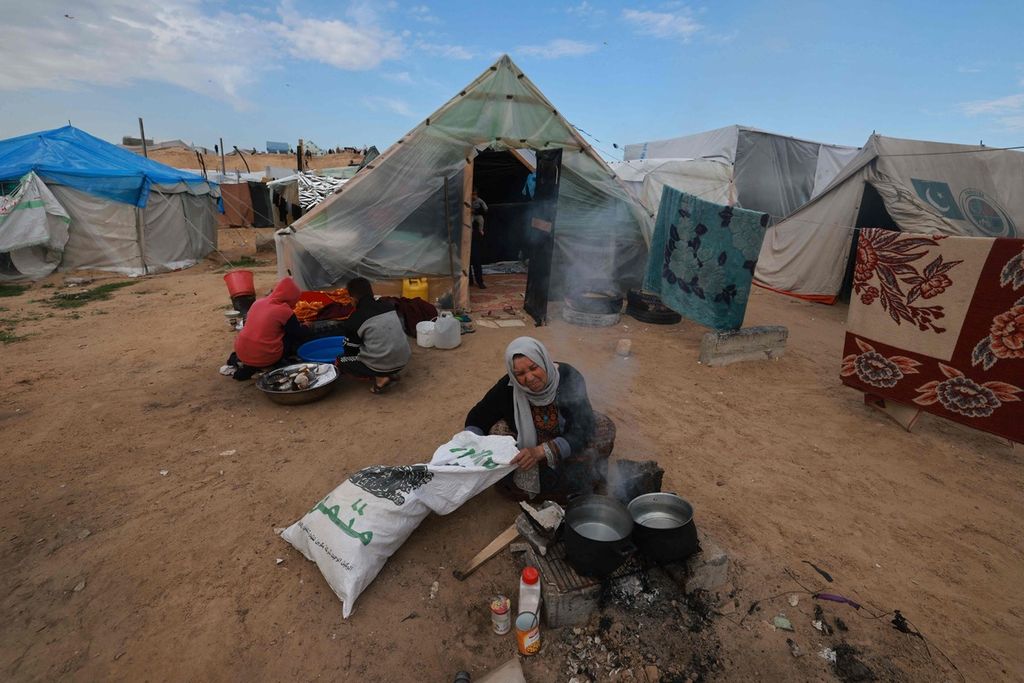 Warga Palestina yang mengungsi dari Khan Younis memasak di tenda pengungsian di Rafah, Jalur Gaza, 15 Februari 2024.  