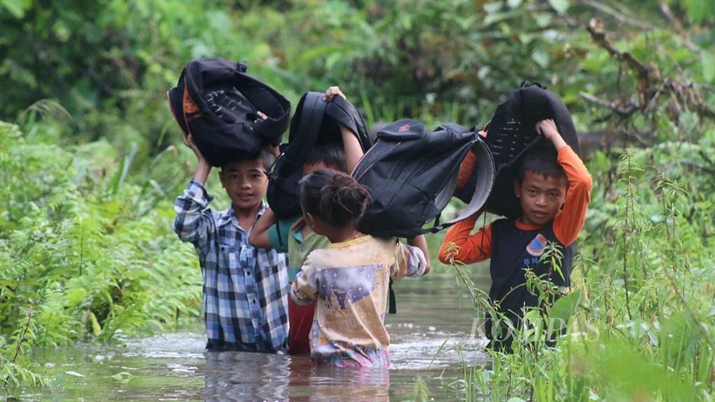Empat siswa Sekolah Dasar Negeri 12 Muntei Filial Salappa berusaha melewati banjir yang menggenangi jalur penghubung Dusun Bekkeiluk dengan Dusun Salappa di Desa Muntei, Kecamatan Siberut Selatan, Kabupaten Kepulauan Mentawai, Sumatera Barat, akhir November 2017.