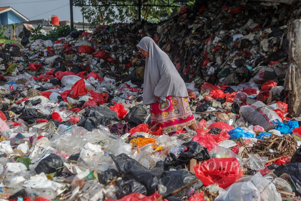 Warga berjalan di antara tumpukan sampah di Jalan Naming D Bothin, Kota Depok, Jawa Barat, Jumat (28/7/2023).