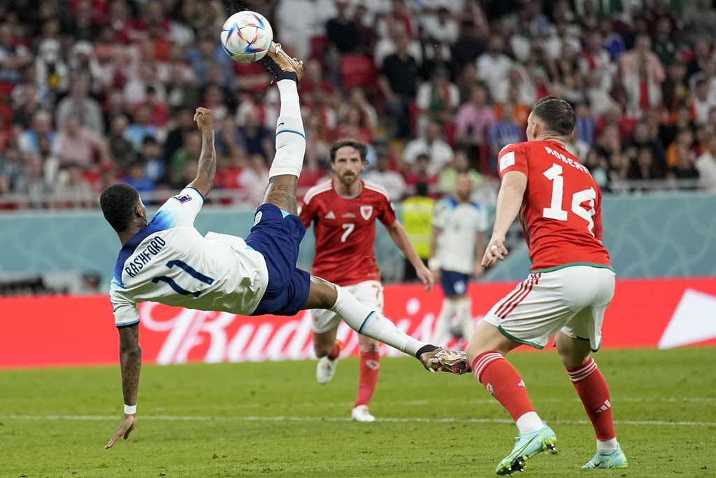 Striker Marcus Rashford dari Inggris menendang bola di pertandingan sepak bola grup B Piala Dunia antara Inggris dan Wales, di Stadion Ahmad Bin Ali di Al Rayyan, Qatar, Rabu (30/11/2022) dini hari WIB. Dua gol Rashford menangkan Inggris 3-0 atas Wales. 