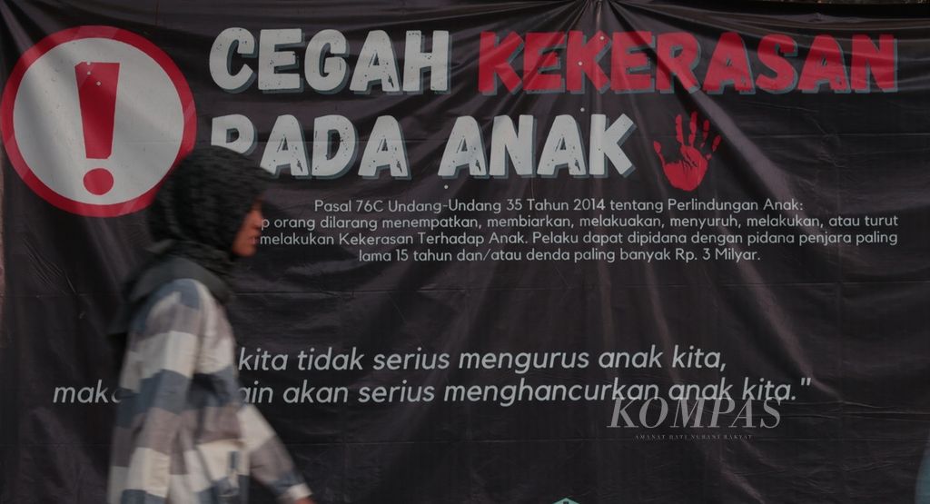 Warga melintasi spanduk kampanye antikekerasan pada anak di kawasan Bojongsari, Depok, Jawa Barat, Minggu (29/10/2023). 