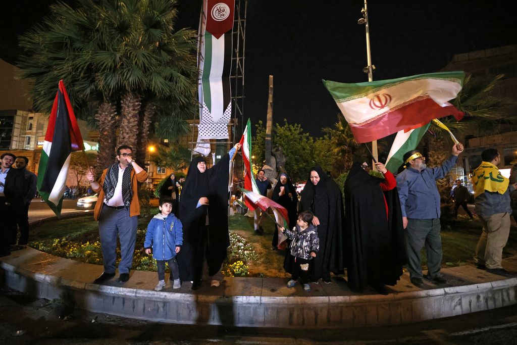 Pengunjuk rasa melambaikan bendera Iran dan Palestina saat mendukung serangan Iran terhadap Israel, di Alun-alun Palestina di Teheran, Iran, 14 April 2024. 
