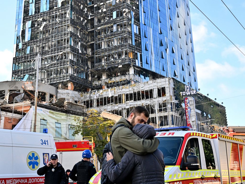 Dua warga berpelukan melihat sebuah bangunan yang rusak setelah roket Rusia membombardir ibu kota Kyiv, Ukraina, Senin (10/10/2022). 