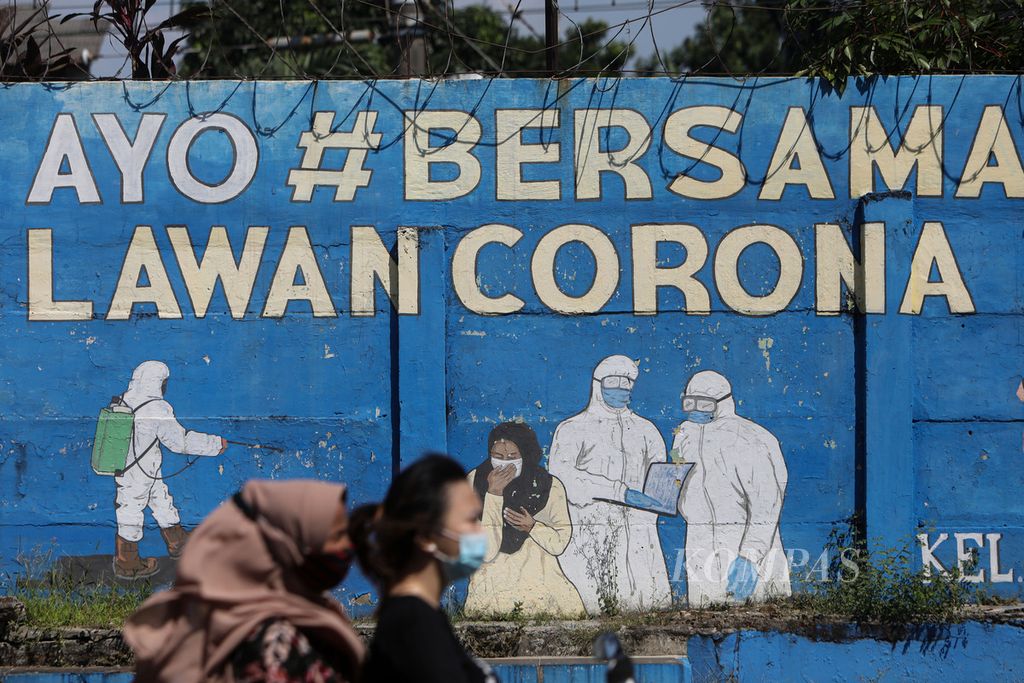 Two female motorbike riders cross a mural with the theme of Covid-19 decorating a wall in Bukit Duri, Tebet, South Jakarta, Monday (16/8/2021). Today, the pandemic is increasingly under control in Indonesia.