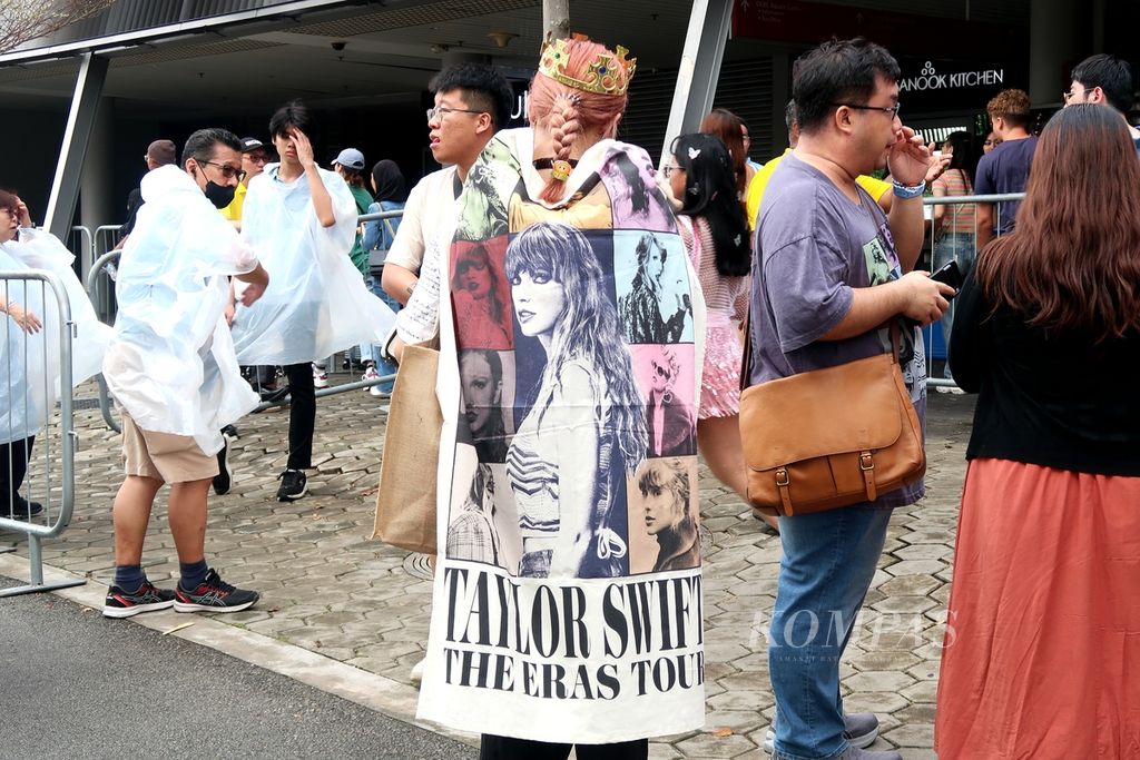 Seorang Swiftie dengan mahkota mengenakan bendera The Eras Tour sebagai jubah sebelum perhelatan konser Taylor Swift: The Eras Tour di National Stadium, Singapura, Minggu (3/3/2024).