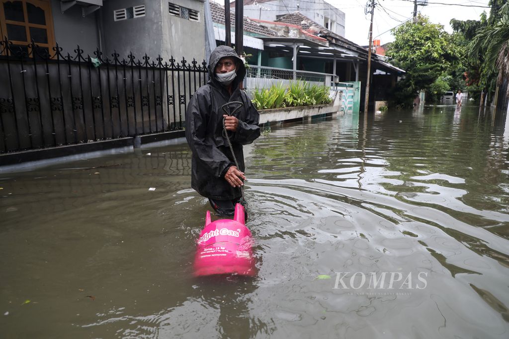 Sukirdhi, menembus banjir saat mengantarkan gas elpiji ke pelangganya yang terendam banjir di Panggung Lor, Semarang, Minggu (7/2/2021). Banjir yang terjadi sejak Sabtu (6/2/2021) kemarim belum sepenuhnya surut.