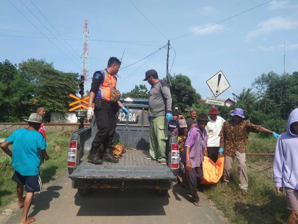 Warga dan petugas mengangkut jenazah korban yang tersambar kereta api di pelintasan sebidang wilayah Cirebon, Jawa Barat, Minggu (11/12/2022). Kecelakaan itu menyebabkan dua orang meninggal dan seorang lainnya luka berat.