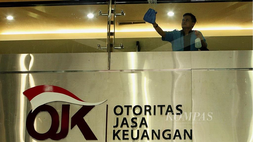 Pekerja membersihkan kaca di Kantor Otoritas Jas Keuangan (OJK), Jakarta, Senin (13/2/2017).