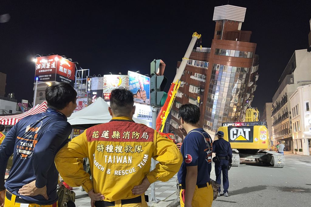 Petugas keselamatan di Hualien, Taiwan timur, Kamis (4/4/2024), berdiri di dekat gedung yang miring setelah gempa melanda wilayah itu. 