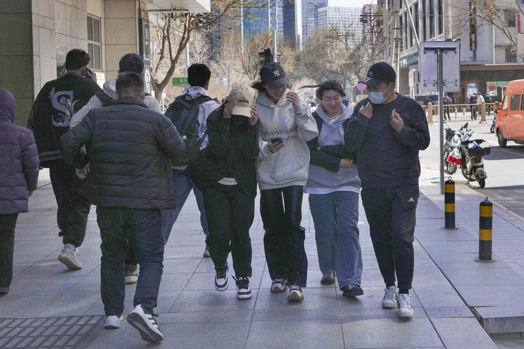 Warga berjalan di trotoar tepi ruas jalan di Beijing, China, Selasa (19/3/2024).  