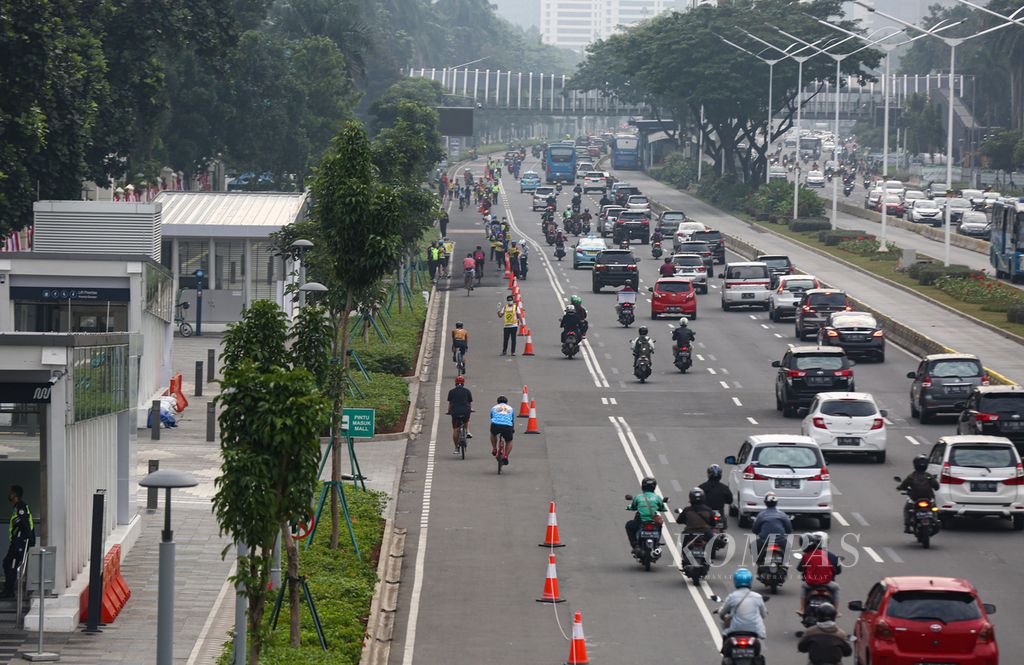 Pengendara sepeda melaju di jalur sepeda sementara atau <i>pop up bike lane </i>di Jalan Jenderal Sudirman, Jakarta, Jumat (3/7/2020).