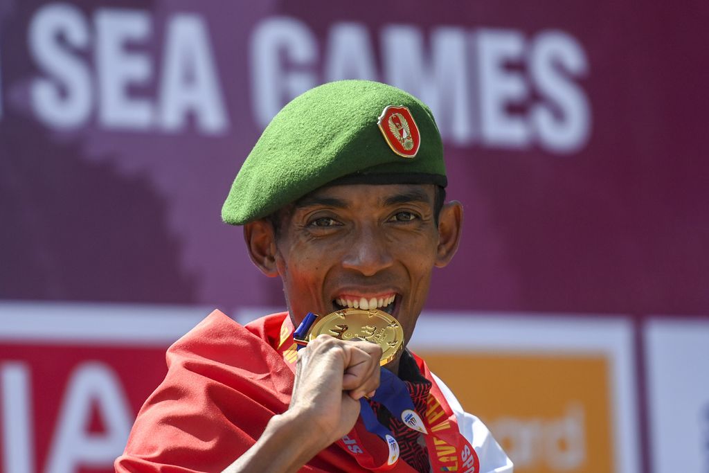 Pelari putra Indonesia, Agus Prayogo, mengigit medali emas saat penyerahan medali maraton SEA Games 2023 di kawasan situs warisan budaya dunia UNESCO Angkor Wat, Siem Reap, Kamboja, Sabtu (6/5/2023). Pelari asal Jawa Barat tersebut berhasil meraih medali emas pertama untuk cabang atletik. 