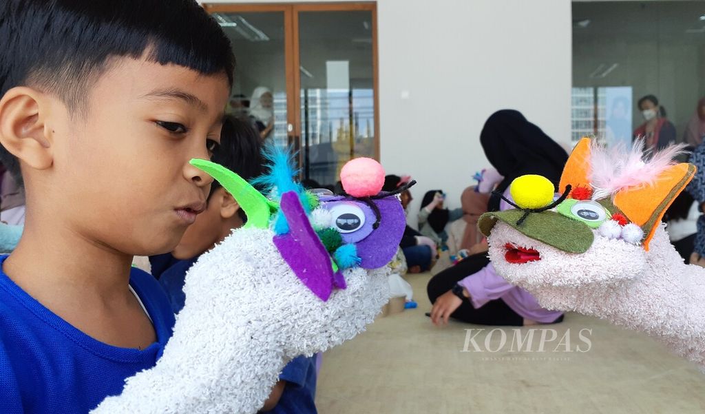 Seorang anak bermain boneka tangan yang dirangkai sendiri saat mengikuti perayaan Hari Anak Nasional 2023 di Perpustakaan Jakarta, Sabtu (22/7/2023). 