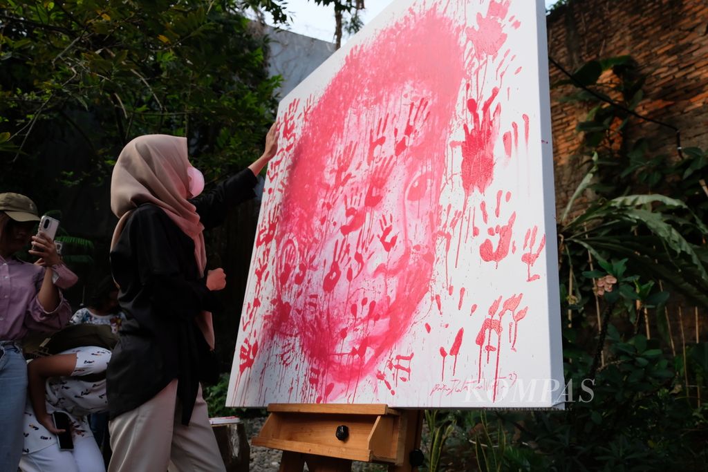 Pengunjung pameran seni "Speak Up" memberi cap tangan di lukisan karya perupa Prajna Dewantara pada Sabtu (22/7/2023) di Jakarta. Cap itu merupakan simbol perjanjian publik untuk bekerja sama menghentikan kekerasan seksual. 