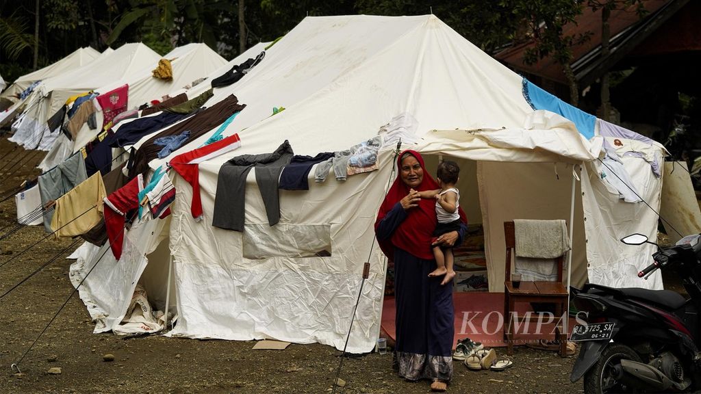 Seorang ibu menggendong anaknya keluar dari tenda pengungsian di Nagari Kajai, Kecamatan Talamau, Kabupaten Pasaman Barat, Sumatera Barat, Senin (28/2/2022). 