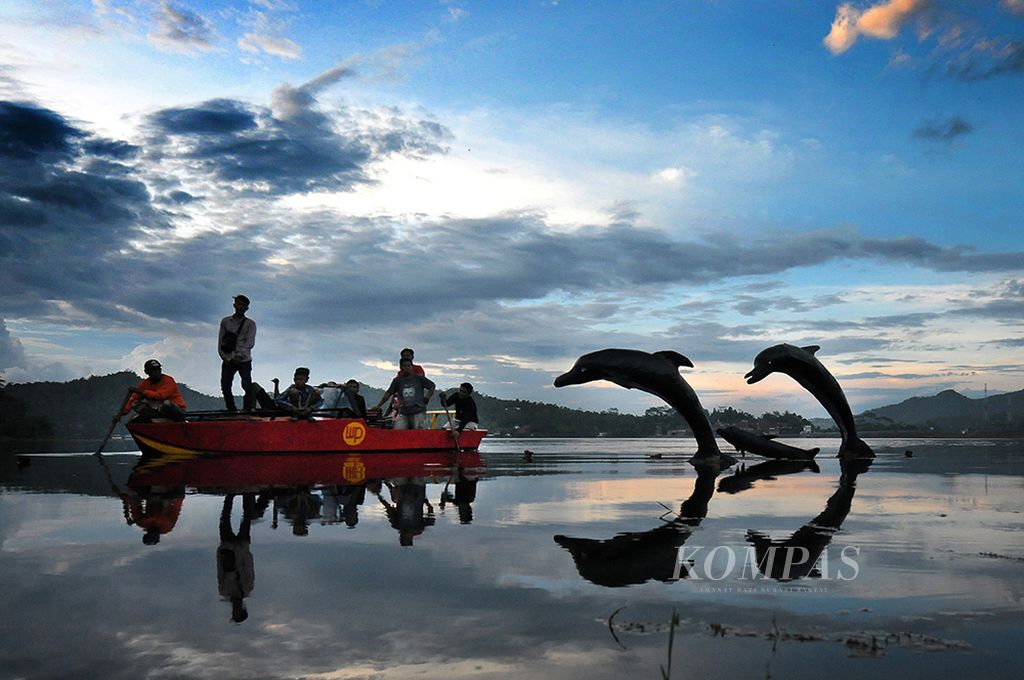 Pengunjung menikmati Waduk Penjalin, di Desa Winduaji, Kecamatan Paguyangan, Kabupaten Brebes, Jawa Tengah. Tempat ini ramai dikunjungi orang setelah sejumlah pemuda desa menyediakan beberapa titik untuk berfoto, seperti patung lumba-lumba ini.