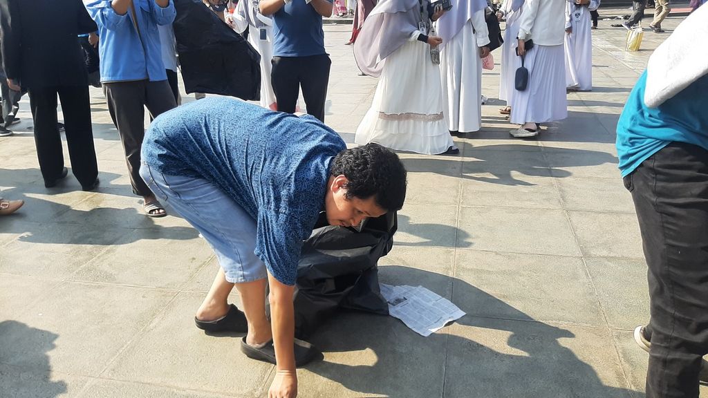 Salah satu anggota Orang Muda Katolik Katedral Jakarta memungut sampah koran bekas di lingkungan Masjid Istiqlal, Jakarta, Sabtu (22/4/2023),