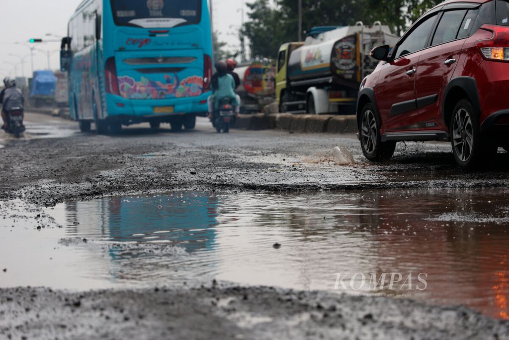 Kendaraan melintasi jalan rusak karena terendam banjir selama beberapa hari di Kaligawe, Kota Semarang, Jawa Tengah, Kamis (5/1/2023). 