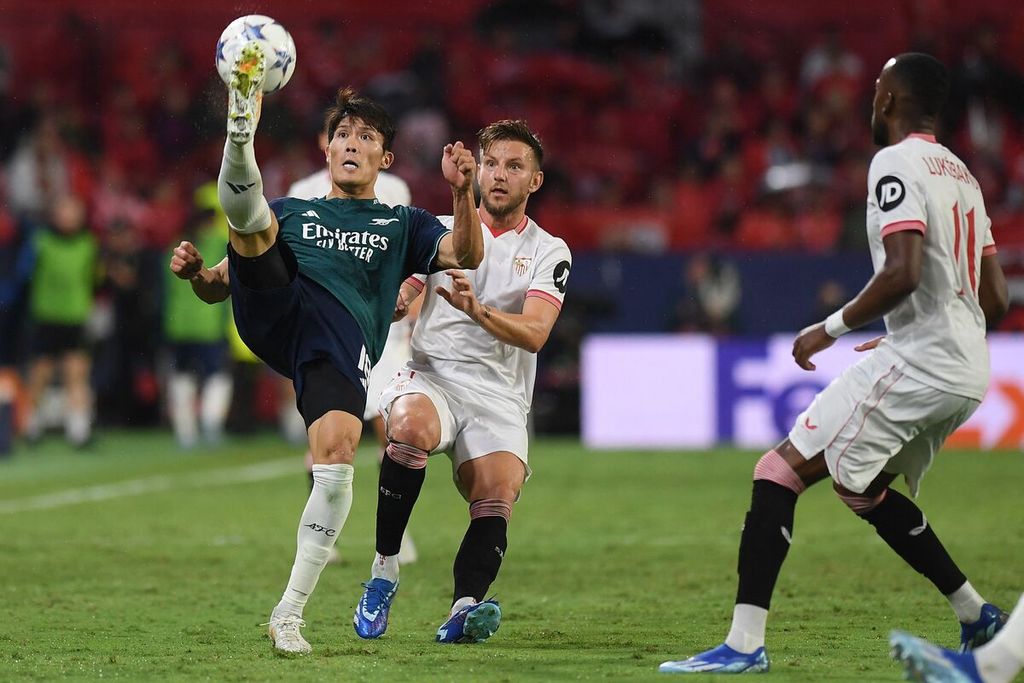 Bek Arsenal, Takehiro Tomiyasu, berebut bola dengan gelandang Sevilla, Ivan Rakitic, dalam pertandingan Liga Champions Grup B antara Sevilla dan Arsenal di Stadion Ramon Sanchez Pizjuan, Sevilla, Spanyol, Rabu (25/10/2023) dini hari WIB. 