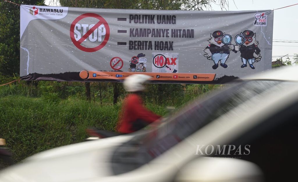Pengendara melintasi spanduk yang dipasang oleh Badan Pengawas Pemilu (Bawaslu) Jawa Timur di Jalan Raya Sukodono, Sidoarjo, Jawa Timur, Senin (11/12/2023). Spanduk tersebut berisi imbauan untuk stop politik uang, kampanye hitam, dan hoaks.