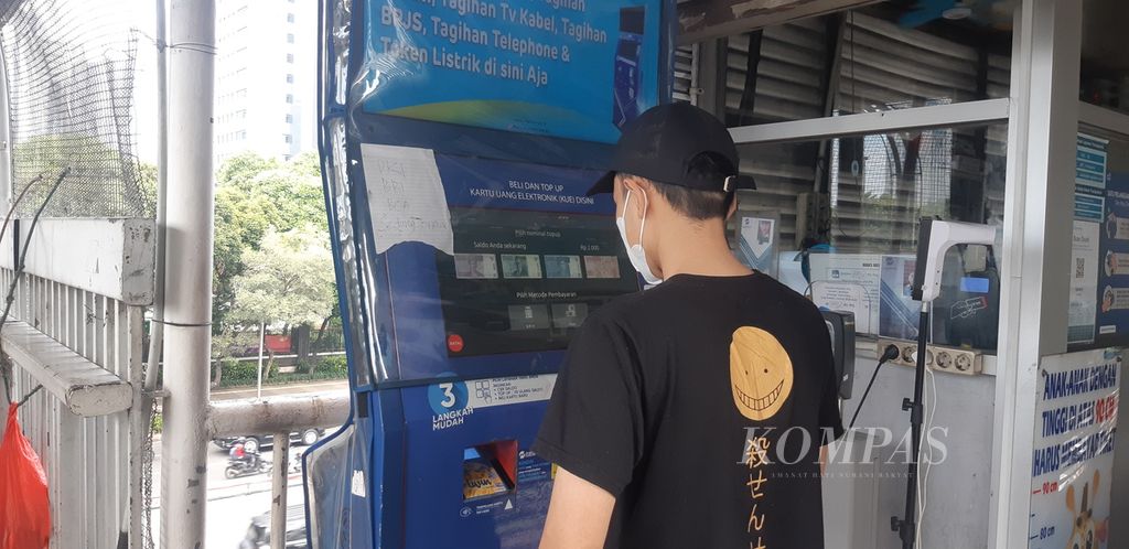 Seorang pelanggan Transjakarta mengisi kartu uang elektronik mereka di pintu masuk Halte Semanggi, Jakarta Selatan, Selasa (4/10/2022).