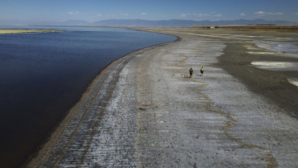 Warga berjalan kaki di area yang surut setelah rekor level air terendah terlihat di Great Salt Lake, Utah, Amerika Serikat, Selasa (6/9/2022). Gelombang panas berkepanjangan telah memecahkan rekor di Utah ketika saat itu suhu udara mencapai 40,5 derajat celcius.