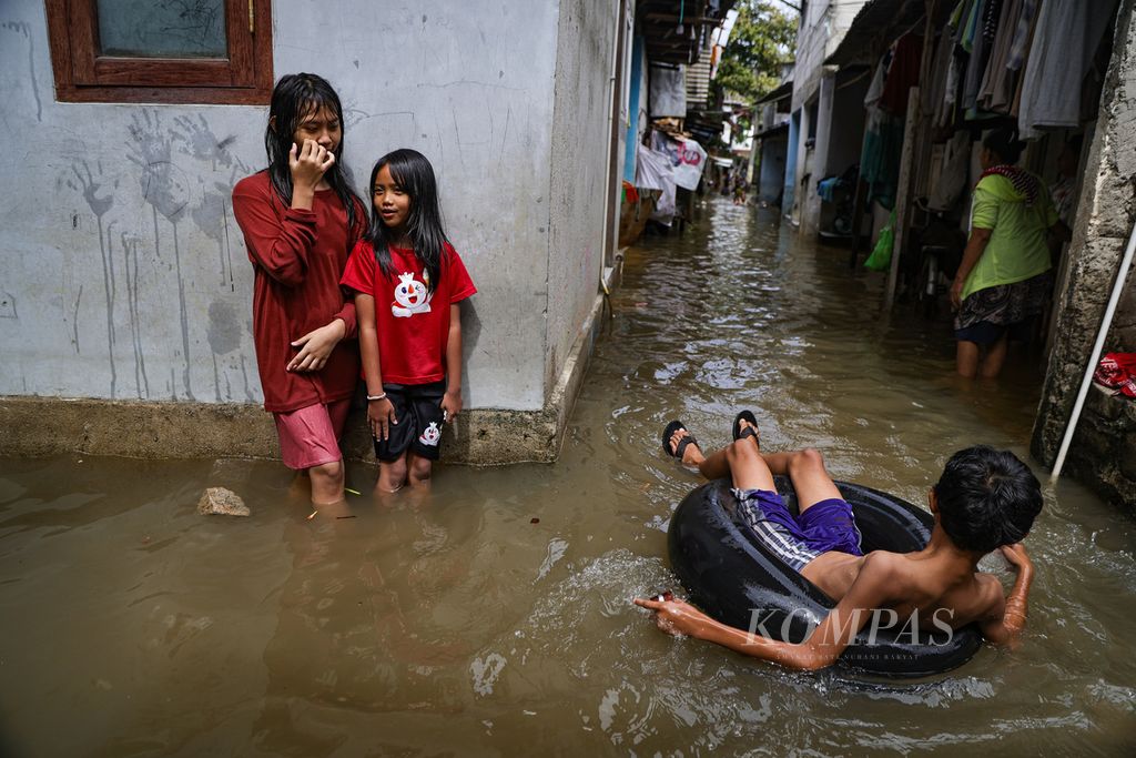 Anak-anak bermain saat banjir di RT 016 RW 004 Kelurahan Rawa Buaya, Cengkareng, Jakarta Barat, Minggu (7/7/2024). Banjir masih menggenangi wilayah ini.