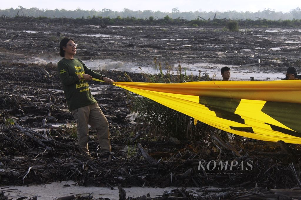 Ketua Tim Kampanye Hutan Greenpeace Arie Rompas ikut menarik spanduk besar yang merupakan aksi kritik mereka terhadap program strategis nasional (PSN) food estate di Kalteng, Kamis (10/11/2022). Mereka menginginkan program yang menyumbang krisis iklim itu dihentikan segera.