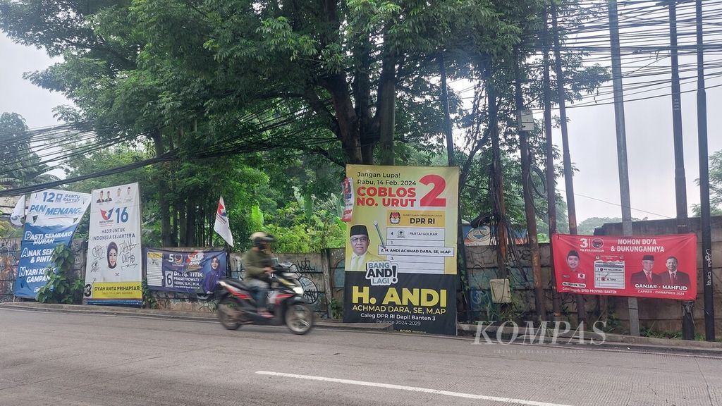 Seorang pengendara melintas di Jalan Siliwangi, Pamulang, Tangerang Selatan, yang tepi jalannya dipenuhi baliho dan spanduk caleg dari sejumlah partai, Selasa (30/1/2024).