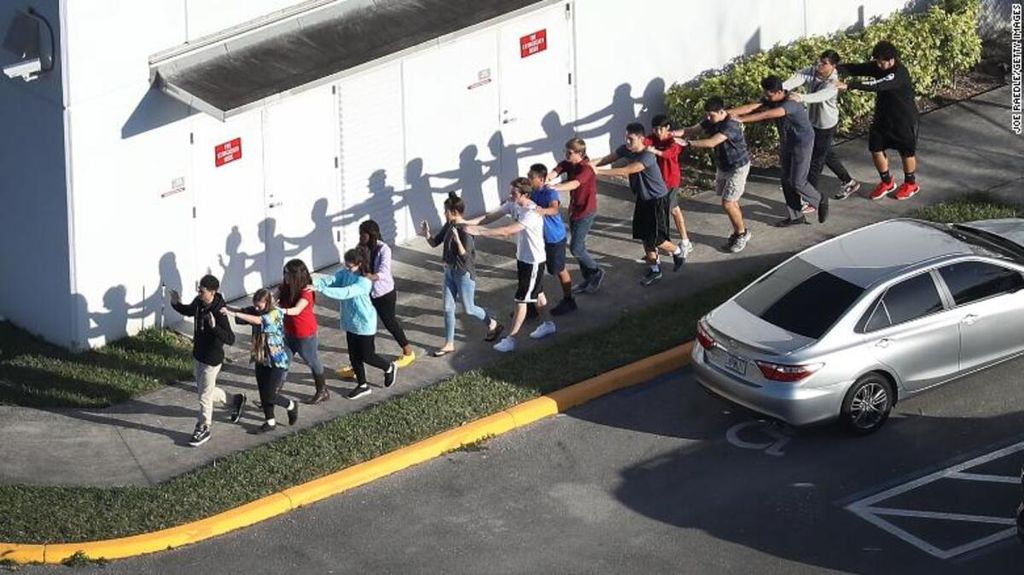 Para siswa SMA Marjory Stoneman Douglas, Parkland, Florida, AS berbaris keluar dari sekolah sambil beriringan.