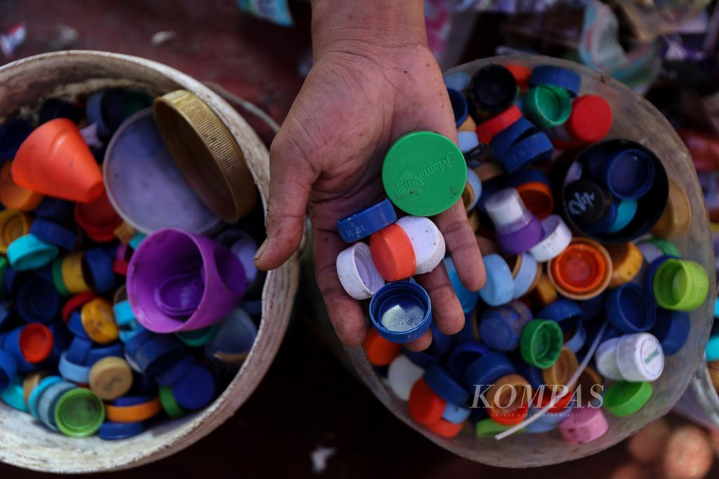 Tangan petugas memperlihatkan tutup botol plastik yang sudah dipisahkan di TPS 04 Bambu Apus, Kecamatan Cipayung, Jakarta Timur, Senin (22/4/2024). Tumpukan sampah plastik yang berada di TPS 04 Bambu Apus dimanfaatkan kembali untuk didaur ulang.