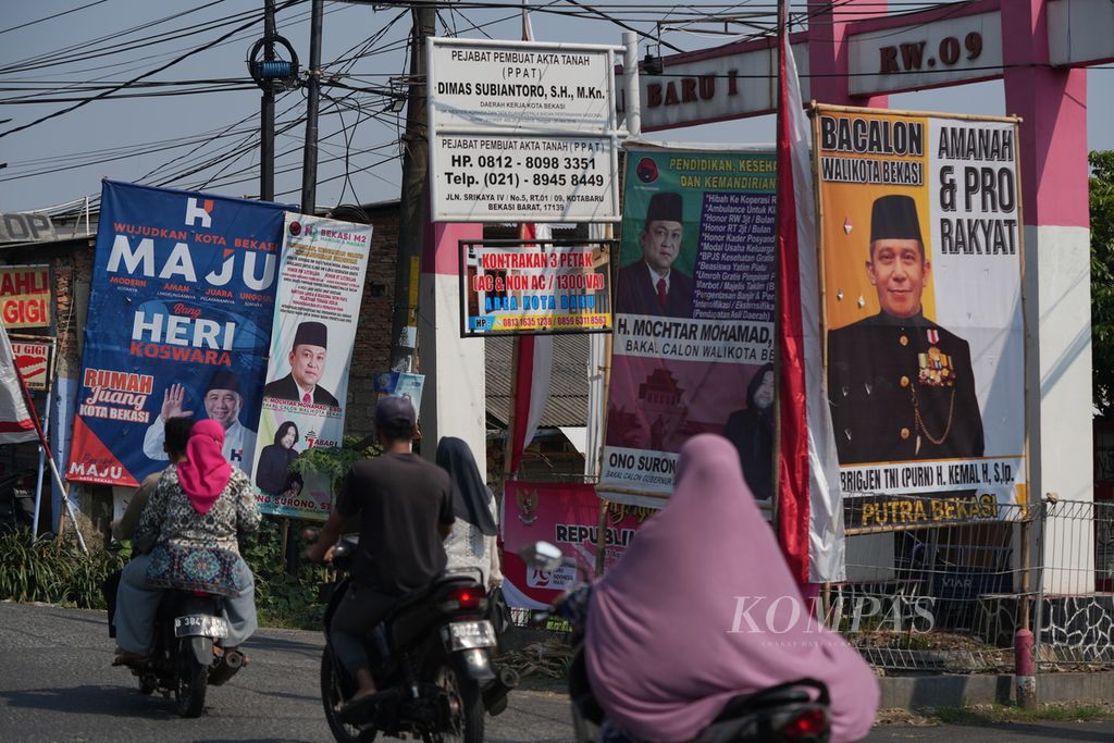 Warga melintasi baliho bakal calon wali kota Bekasi dan gubernur Jawa Barat yang akan maju dalam Pilkada di Bekasi Barat, Kota Bekasi, Jawa Barat, Senin (19/8/2024).