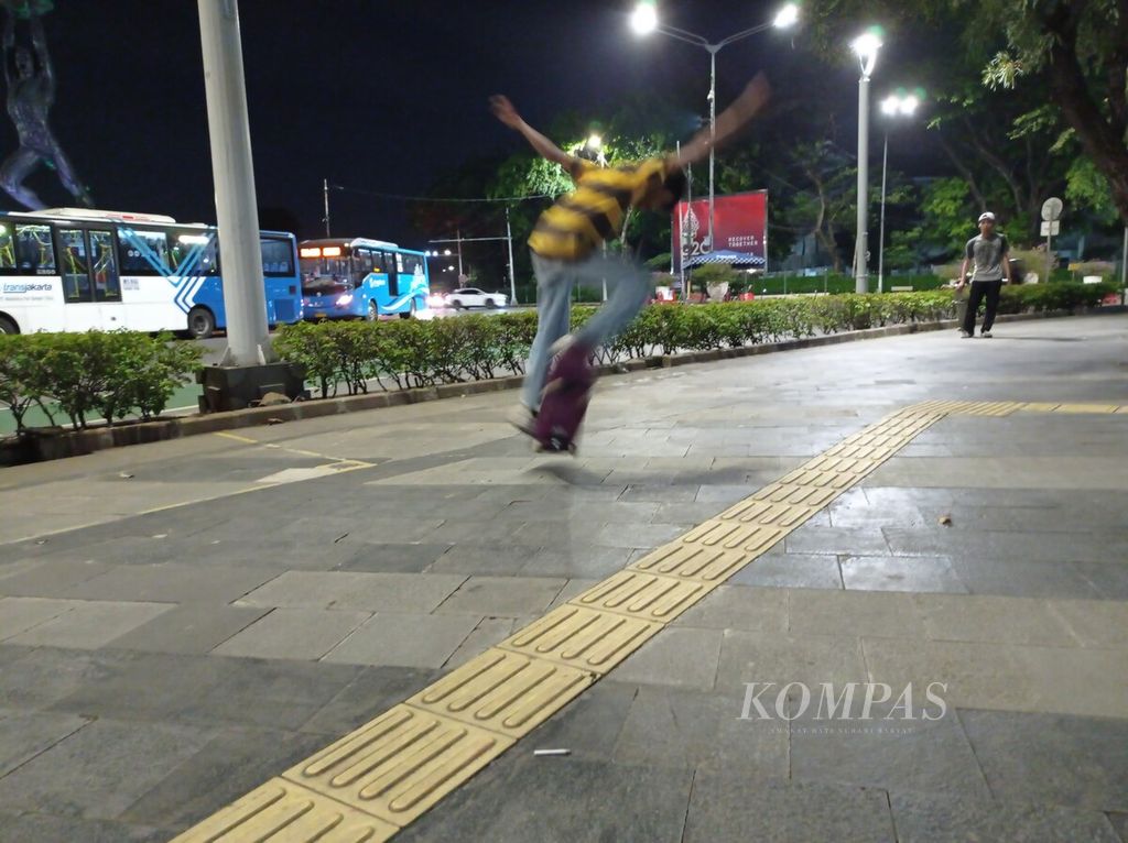 Salah satu pemain papan seluncur beraksi di trotoar dekat Bundaran Senayan, Jakarta, Senin (4/4/2022).