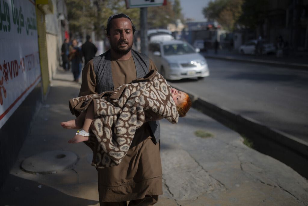 Seorang pria membopong seorang anak yang terluka sambil berlari meninggalkan lokasi ledakan di Kabul, 2 November 2021. Sejumlah warga sipil terbunuh dalam ledakan tersebut. 