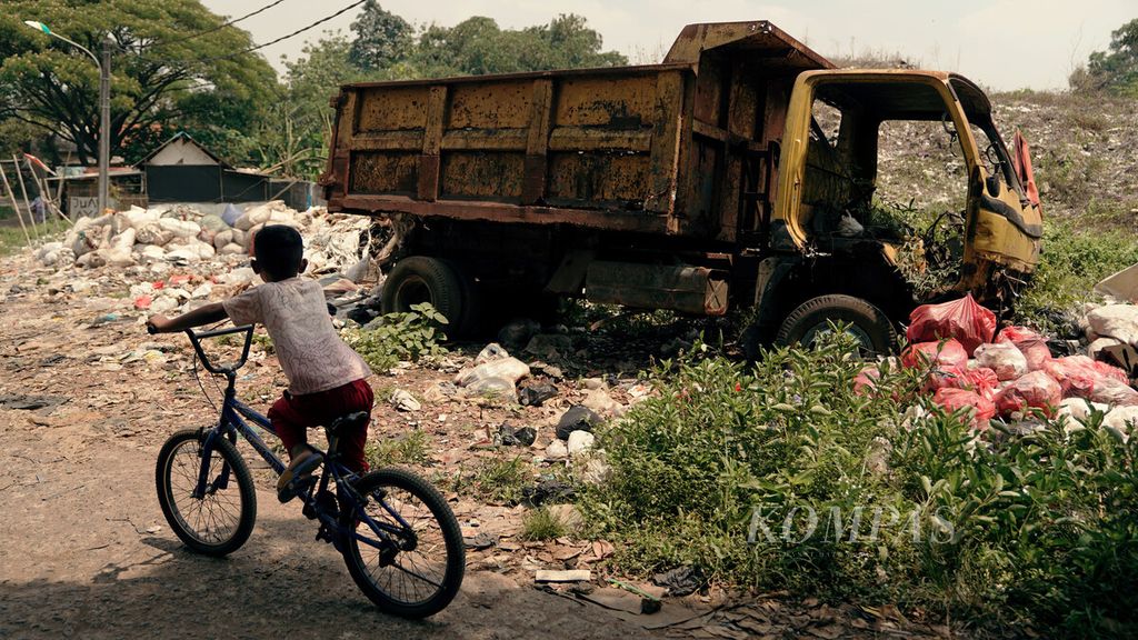 Anak bersepeda melintasi bangkai truk sampah di sekitar TPST Bantargebang, Kota Bekasi, Jawa Barat, Selasa (21/9/2021). 