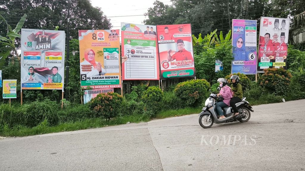 Pengendara sepeda motor melintas di jalan yang penuh dengan baliho calon anggota legislatif di Kecamatan Samarinda Ulu, Kota Samarinda, Kalimantan Timur, Kamis (21/12/2023).