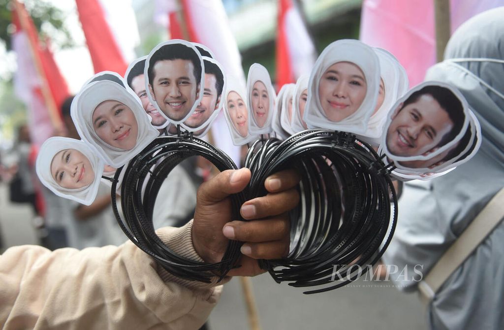 Penjual menawarkan bando bergambar Khofifah dan Emil saat pendaftaran pasangan calon gubernur dan wakil gubernur di Kantor KPU Jawa Timur, Surabaya, Rabu (28/8/2024). 