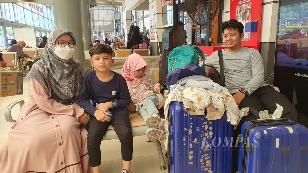 Mirza Sena (34) bersama keluarga duduk di ruang tunggu Stasiun Pasar Senen, Jakarta Pusat, Kamis (28/3/2024), sebelum mudik ke kampung halaman di Kuningan, Jawa Barat.