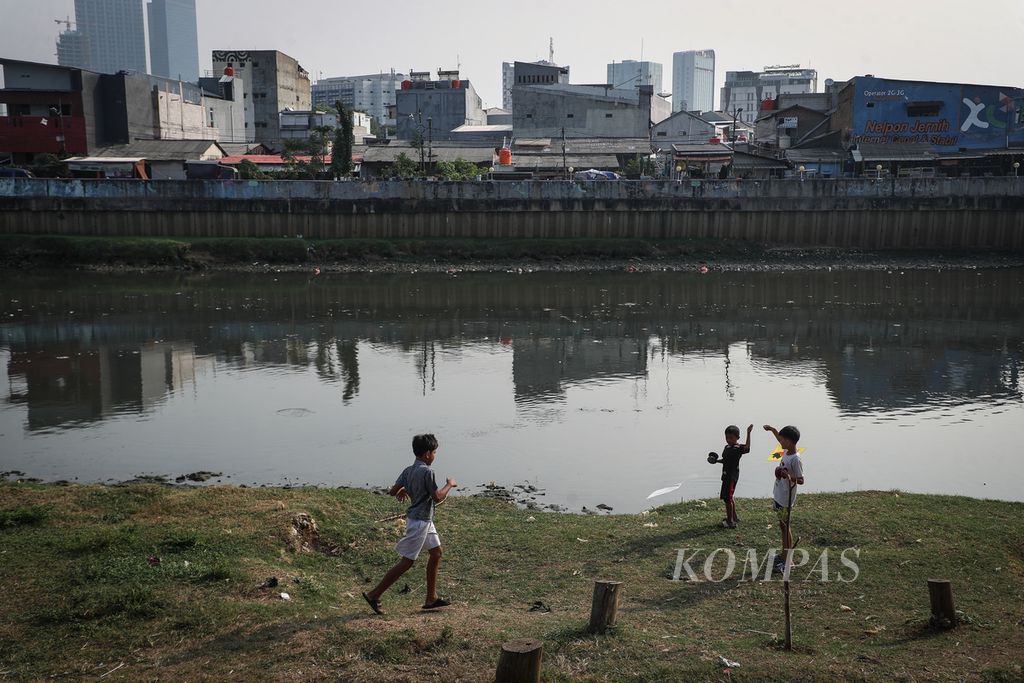 Anak-anak bermain layangan di bantaran Sungai Ciliwung di kawasan Duri Pulo, Jakarta Pusat, Kamis (3/8/2023). Kawasan ini dikelilingi permukiman padat, banyak hunian ditinggali secara turun-temurun atau dihuni oleh keluarga besar.