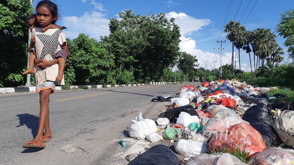 Anak kecil berjalan dekat tumpukan sampah di pinggir Jalan Herman Johanes, Kota Kupang, Nusa Tenggara Timur, Minggu (12/12/2021). Titik itu bukan merupakan tempat pembuangan sampah sementara.