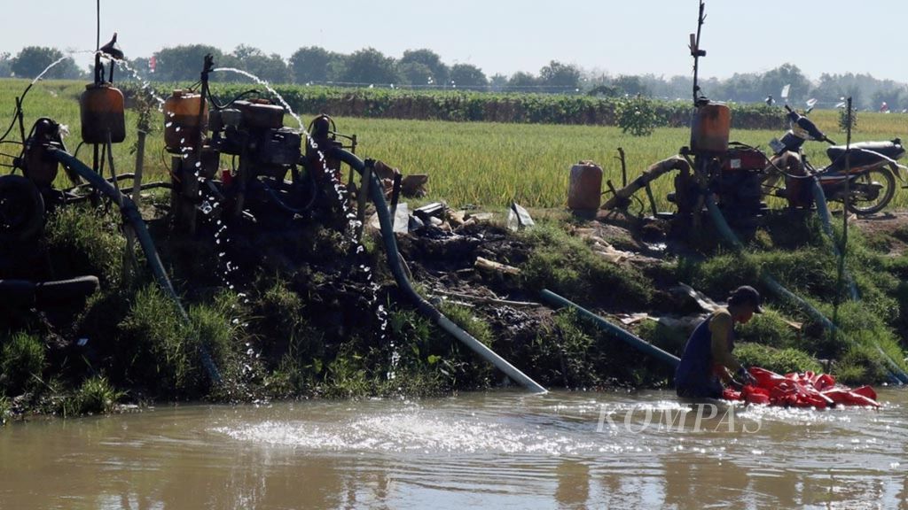 Petani menggunakan mesin pompa air di saluran irigasi Cikedung, Kabupaten Indramayu, Jawa Barat, Senin (22/7/2019). Kekeringan membuat petani menggunakan mesin pompa untuk menyedot air ke sawah. Ongkos produksi pun bertambah.